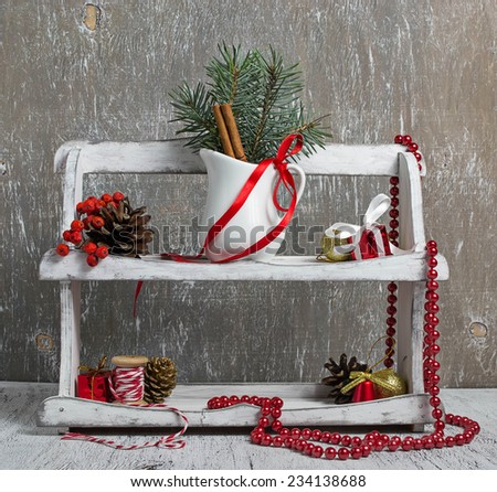 Christmas items in wooden shelf:  pinecone, tape, cinnamon, fir branch, beads, thread, gift box