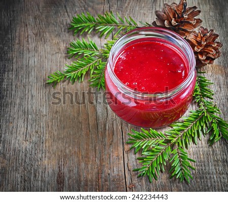 Sweet cranberry jam in jar on wooden background