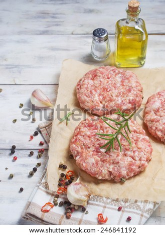 Raw hamburger meat with pepper, garlic, olive oil and salt on butcher paper