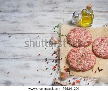 Raw hamburger meat with pepper, garlic, olive oil and salt on butcher paper. Space for text