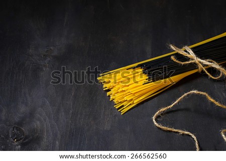 Bunch of black and yellow spaghetti on dark background. Selective focus. Copy space background