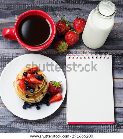 Breakfast with pancakes, coffee, milk and open notebook. Selective focus, top view