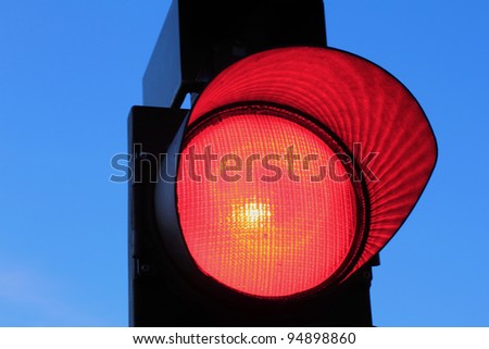 Red traffic light against a bright blue sky