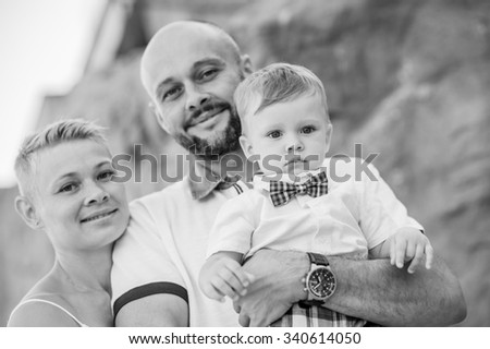 Black and white (b&w) family outdoors portrait. Mother, father in white clothes and their son in white clothes with plaid bow tie