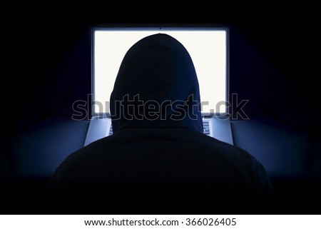 Hacker with laptop wearing hoodie