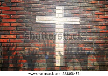 Jesus is light for way of life. Hand's shadows over cross channel on brick wall.