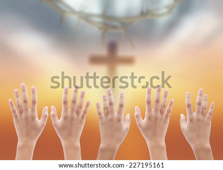 Human raising hands over blurred crown of thorns and the cross on a sunset.