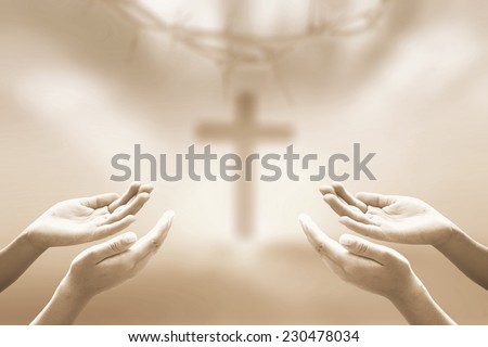 Sepia tone, hands of man praying over blurred crown of thorns and the cross on a sunset.