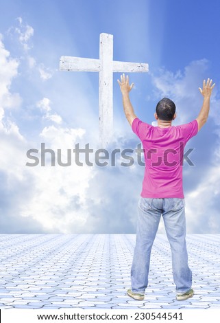 A man raising hands on stone paving over the cross on beautiful sky.