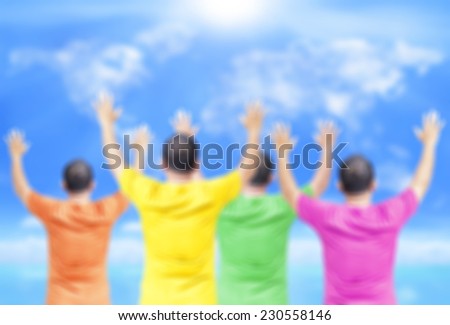 Blurred people wearing colorful shirt raising hands on world map of clouds background