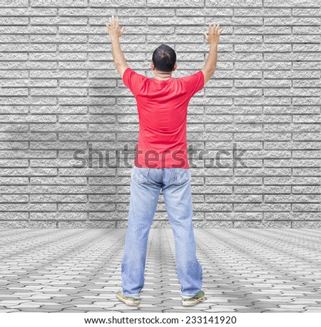 A man raising hands on stone wall and paving over shadow of the cross.