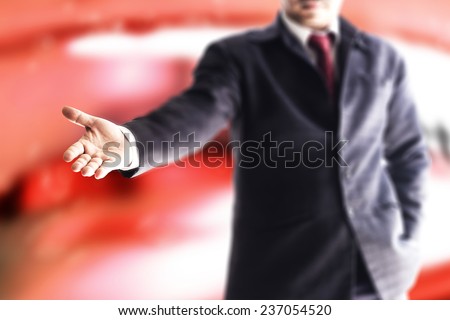 A business man with an open hand ready to seal a deal over red tone office.
