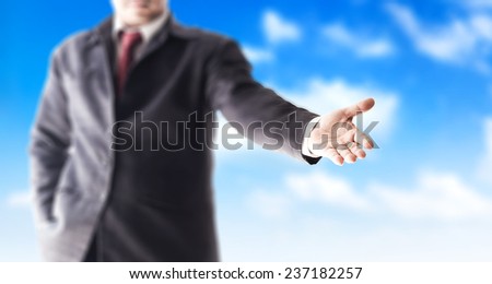 A business man with an open hand ready to seal a deal over blue sky background.