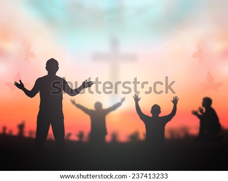 Silhouette people raising hands over blurred crown of thorns and the cross on autumn sunset background.