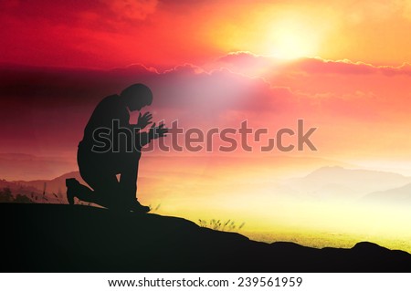 Silhouette human kneeling and praying over over beautiful sunset background. World Mental Health Day concept.