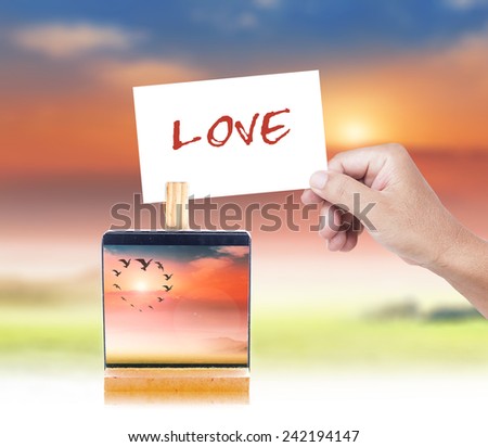 Human hand holding a handwritten LOVE and paper clip over the actual location.