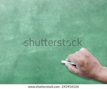 Human hand writing with chalk on green board.