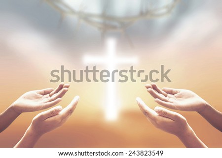 Two people open empty hands with palms up, over blurred crown of thorns and the white cross on beautiful sunset background.