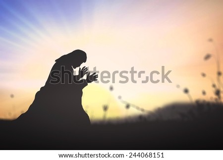 Human kneeling over sunset background.