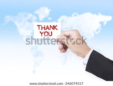 Asian business man holding a handwritten THANK YOU over blurred world map of clouds background.
