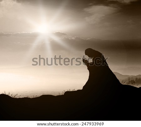 Silhouette Jesus Christ of Nazareth or believer kneeling and praying over beautiful sunrise or sunset background. Sepia tone.
