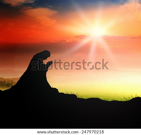 Silhouette human kneeling over sunset background.