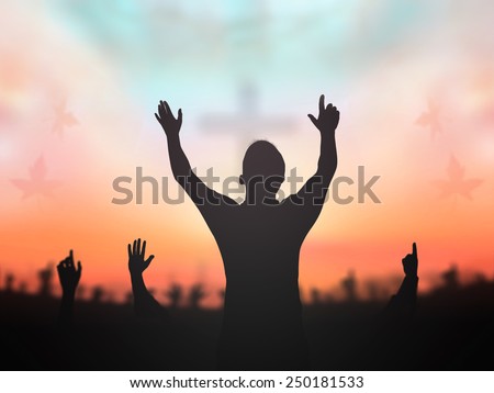 Silhouette people raising hands over blurred crown of thorns and the cross on golden autumn sunset background.