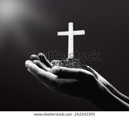 Black and white human hand holding the wooden white cross.