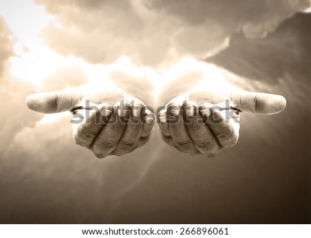Sepia tone. Human open empty hand with palms up over amazing sky background.