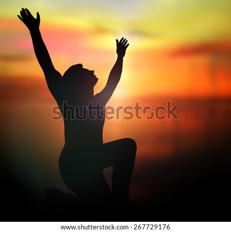 Silhouette human raising hands over blurred nature background.