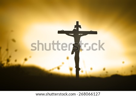 Golden light. Silhouette Jesus and the cross over blurred beautiful sunset background.