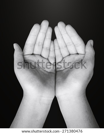 Black and white children open empty hands with palms up. Human hands of prayer in dark room background.