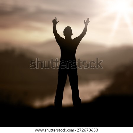Sepia tone. Silhouette of man with hands raised to beautiful sunset background. World Mental Health Day concept.