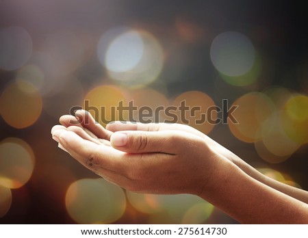 Children open empty hands with palms up. Human hands of prayer over candle light in dark room background.