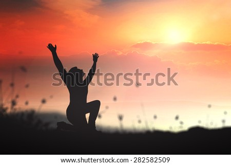 Silhouette people kneeling and raising hands over beautiful nature background.