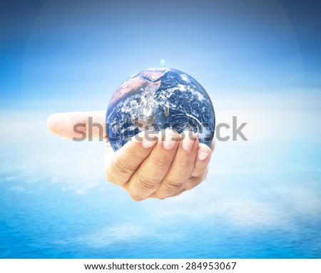 Planet in human hand over blurred beautiful blue sky and oceans background. Environment, Earth Day, World Environment Day and Creation from God concept. Elements of this image furnished by NASA.
