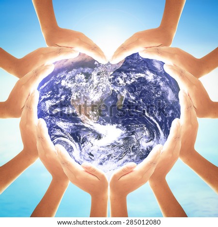 Earth globe in 12 hands for heart shape over blue sky background. Environment, Earth Day, World Environment Day and Creation from God concept. Elements of this image furnished by NASA.