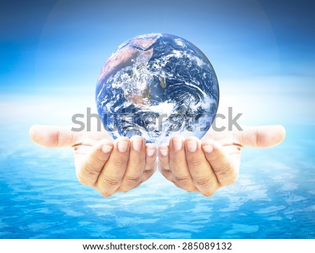 Planet in human hand over blurred beautiful blue sky and oceans background. Environment, Earth Day, World Environment Day and Creation from God concept. Elements of this image furnished by NASA.