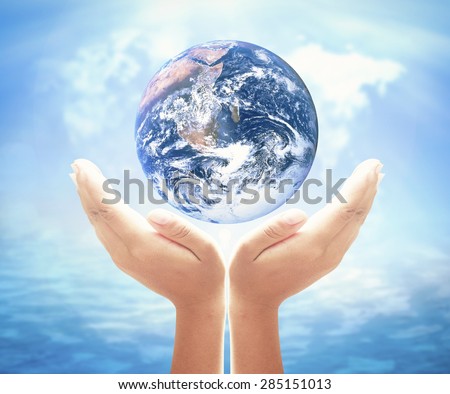 Planet in human hand over blurred world map of clouds and oceans background. Environment, Earth Day, World Environment Day and Creation from God concept. Elements of this image furnished by NASA.