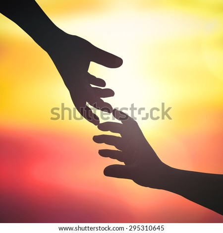 Silhouette human hands or Adam\'s hand reaching to hand of God over abstract blurred nature background. Light of hope from heaven concept.