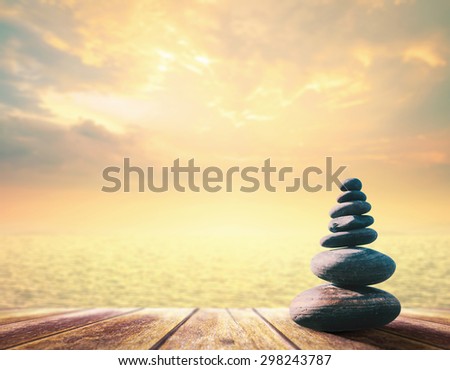 Balanced seven Zen stones on wooden paving and blurred beautiful autumn sunset background. World Mental Health Day concept.