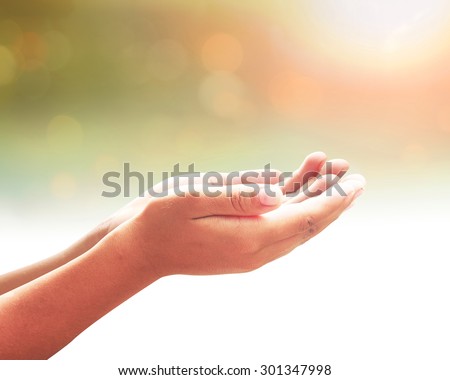 Healing Amazing Light - Human healer with hands open palm up surrounded by a ray white light. Praying hand over blurred sunset background.