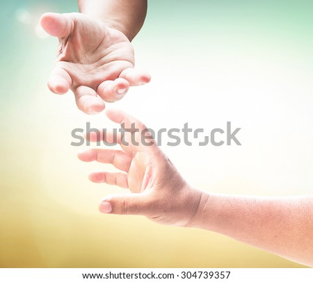 Hand of a man reaching to hand of GOD, or hand holding puzzle over blurred beautiful sunrise or sunset background.