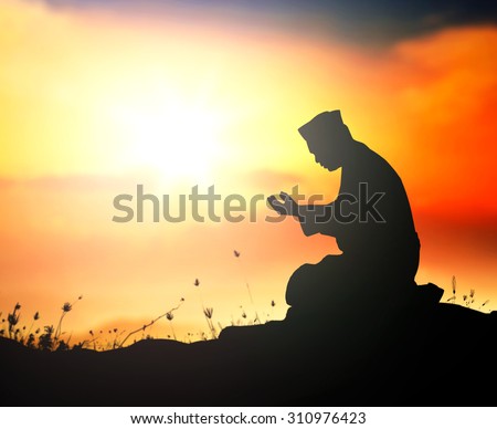 Silhouette muslim man sitting and praying at golden autumn sunset background during the month of ramadan.