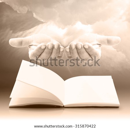 Sepia tone. Blank opened book, diary, photo album over human open empty hand with palms up over amazing blue sky background. Book of life concept.