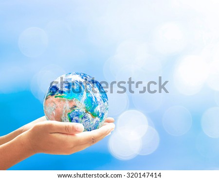 Planet in human hands on beautiful blue bokeh nature background. Environment concept. Elements of this image furnished by NASA.
