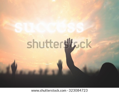 Silhouette Businessman raising hands over text for SUCCESS on beautiful sunset background.
