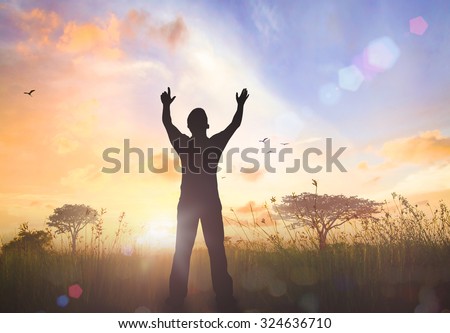 Silhouette of man with hands raised to beautiful autumn sunset background. A disabled man standing up. Positive concept of cure, recovery, medical miracle, hope, insurance etc.