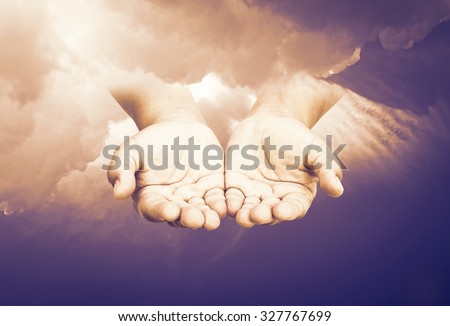 Sepia tone. Human open empty hand with palms up over amazing sky background. Hand of God concept. Help for refugee concept. Dignity concept.