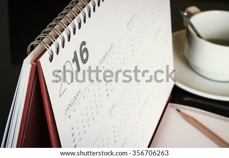 Desktop calendar sitting on desk showing year of 2016. Home office table with stationary, calendar, coffee, paper, pencil, January, Happy New Year, Beginning, Start, Life, office, Home Leap concept.